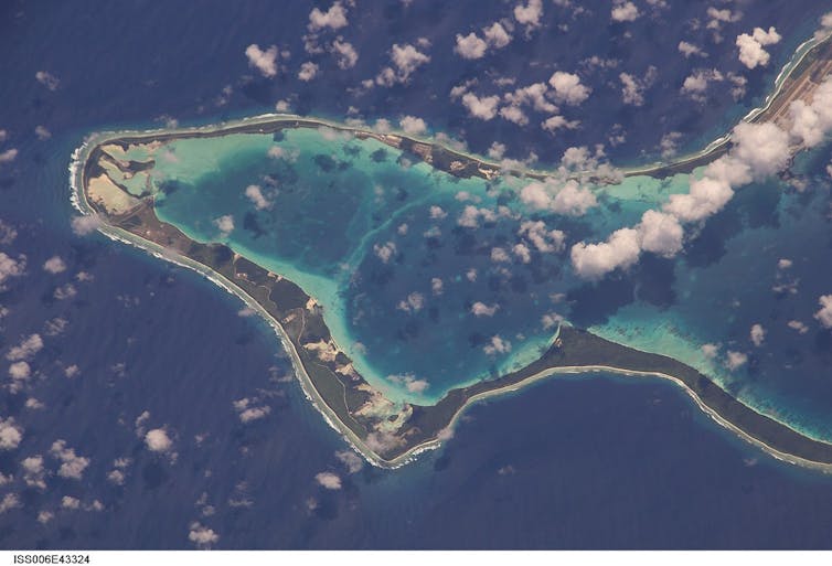 A view from above of an island ridge, water all around it and in the middle of it.